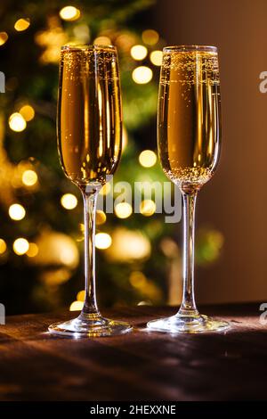 Zwei Gläser Champagner mit weihnachtlichen festlichen Lichtern vor verschwommenem Hintergrund. Feierlaune und Nahaufnahme Stockfoto