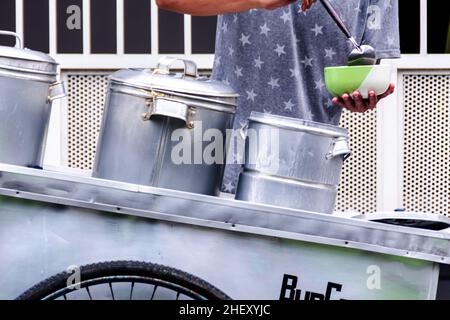 Man Street Food-Verkäufer, der den traditionellen indonesischen Porridge mit grünen Bohnen auf seinem silbernen Wagen serviert Stockfoto