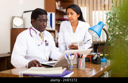 afroamerikanische Ärztin, die mit einer Assistentin am Laptop arbeitet Stockfoto