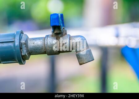 Nahaufnahme des öffentlichen Eisenwasserhähns mit verschwommenem und weichem Fokus im Hintergrund des Stadtparks Stockfoto