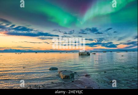 Atemberaubend schöner Sonnenuntergang in Alaska am Cook Inlet mit der Aurora Borealis, die über den Wolken und Bergen auftaucht Stockfoto