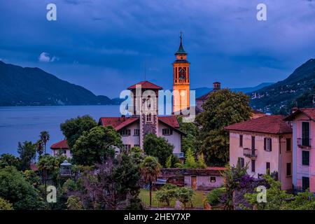 Blick auf die Kirche Chiesa Parrocchiale di San Giorgio, den Lago Maggiore und die umliegenden Berge bei Nacht. Stockfoto