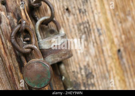 Zwei alte Vorhängeschlösser an einer alten Holztür Stockfoto