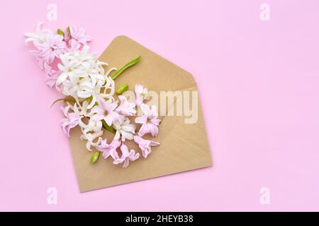 Ein Umschlag mit Hyazinthen-Blüten auf rosa Hintergrund. Flach liegend, Draufsicht. Stockfoto