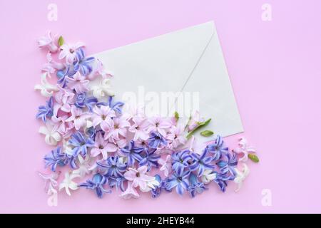 Ein Umschlag mit Hyazinthen-Blüten auf rosa Hintergrund. Flach liegend, Draufsicht. Stockfoto