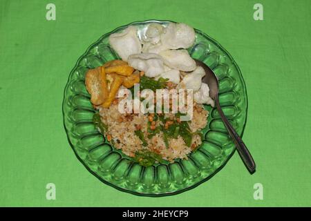 Spezieller gebratener Reis mit Tofu, Crackern, gebratenen Sojabohnen und Frühlingszwiebeln isoliert auf grünem Hintergrund Stockfoto