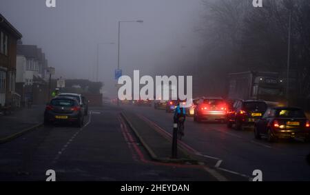 Merton, London, Großbritannien. 13. Januar 2022. Pendler, die am frühen Morgen in einer Schlange in den Vororten im Südwesten Londons in Richtung Zentrum von London fahren, treffen vor Sonnenaufgang auf starken Nebel und Nebel. Quelle: Malcolm Park/Alamy Live News. Stockfoto