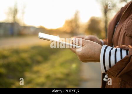 Nahaufnahme der Hände einer Frau, die einen Tablet-pc hält und benutzt, Online-Shopping, Outdoor Stockfoto