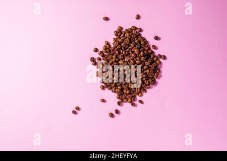 Tasse Kaffee auf einem violetten Hintergrund mit einer Form aus Kaffeebohnen. Ideales Konzept für Cheer Coffee Day, internationalen Barista Day o Stockfoto