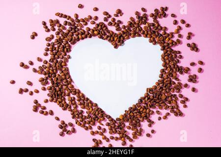 Tasse Kaffee auf einem violetten Hintergrund mit einer Form aus Kaffeebohnen. Ideales Konzept für Cheer Coffee Day, internationalen Barista Day o Stockfoto