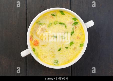 Blick von oben auf eine Schüssel mit Seehechtsuppe mit Rahm und Karotte auf einem Tisch Stockfoto