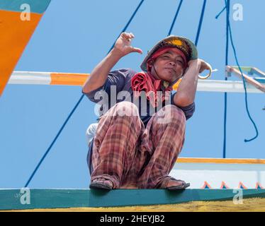 Einer der Besatzung, der sich bei Ebbe auf einem traditionellen philippinischen Fischerboot, einem Basnigan, im Dorf Tinoto, Maasim im Sarangani-Provin, ausruhte Stockfoto