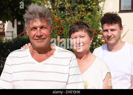 Porträt einer dreiköpfigen kaukasischen Familie. Vater und Mutter sind 62 Jahre alt, ältere Menschen. Ihr Sohn ist ein 32 Jahre alter junger Mann. Sie schauen in den Kameramaran Stockfoto
