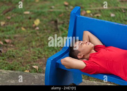 Porträt eines jungen Mannes, der auf einer Parkbank liegt Stockfoto