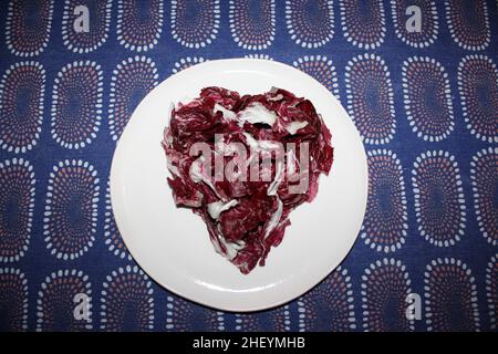 Ein violettes Herz aus italienischem Radicchio auf einem weißen Gericht Stockfoto