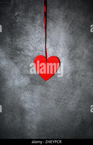 Minimalistische Dekoration, rotes Herz auf strukturiertem grauen Hintergrund, trendige, minimalistische Valentinskarte Stockfoto