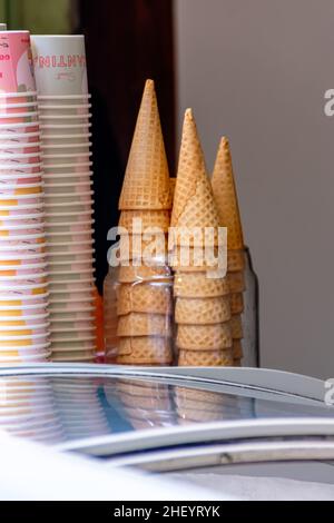Haufen knusprig brauner Eiswaffelkegel und Becher stehen auf dem Laden Stockfoto