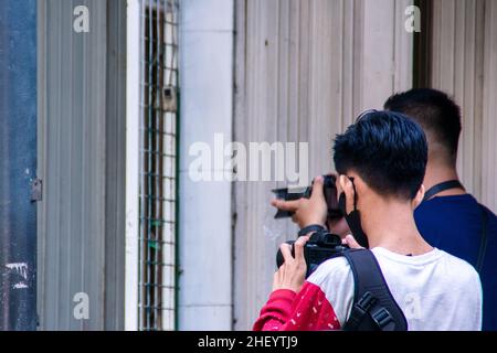 Zwei junge Fotografen, die an ihrem Job arbeiten, um mit ihren eigenen Kameras wunderschöne Aufnahmen auf dem Bürgersteig der Stadt zu machen Stockfoto