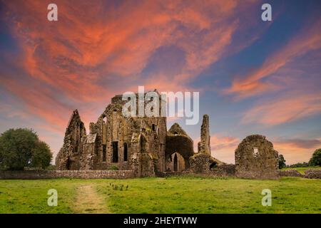 Ruinen der Hore Abbey bei Sonnenuntergang mit rötlichen Wolken, in der Nähe des irischen Dorfes Cashel. Erbaut von Benediktinermönchen im 13th. Jahrhundert. Stockfoto