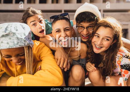 Zeit mit Freunden. Eine Gruppe von Freunden der Generation z lacht fröhlich, während sie draußen in der Stadt zusammen hängen. Glückliche junge Freunde havi Stockfoto