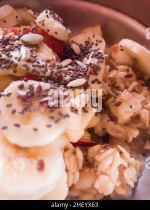 Nahaufnahme des Haferflocken-Frühstücks mit Banane, Samenmischung und Milch. Gesundes Frühstück. Selektiver Fokus. Stockfoto