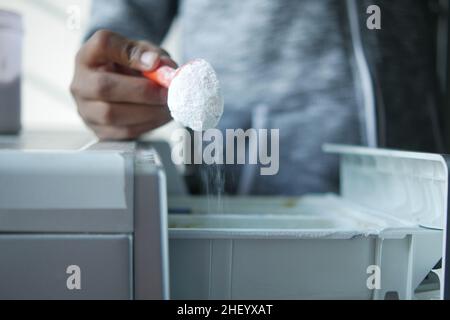 Gießen von Waschpulver in Kunststoffschale der Waschmaschine Stockfoto