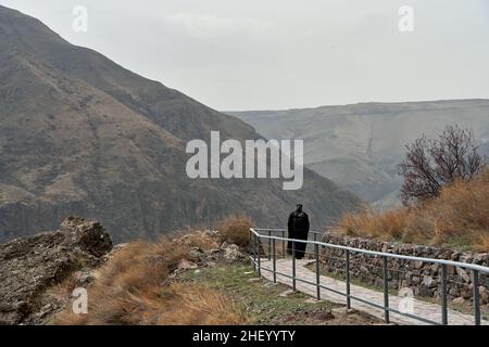 Der Ruzin-Priester in einer Soutane spaziert durch die Höhlenstadt im Felsen. Stockfoto