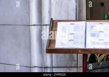 Brauner Holztisch mit Speisekarte vor dem Restaurant auf dem Bürgersteig der Stadt Stockfoto