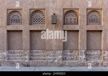 Fensterportale im arabischen Stil in Steinmauer mit Ornamenten, traditionelle arabische Architektur, Al Fahidi, Dubai, Vereinigte Arabische Emirate. Stockfoto