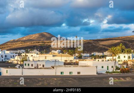 Blick auf das traditionelle weiß getünchte Dorf mit Vulkanen im Hintergrund am Morgen auf der Insel Lanzarote in Spanien Stockfoto