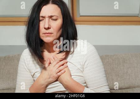 Ältere Frau mittleren Alters mit einem Herzinfarkt. Frau mit Brustschmerzen. Gesundheitsfürsorge und kardiologisches Konzept. Stockfoto