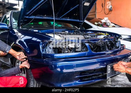 Unter Reparatur blaues Auto mit vielen unmontierten Teilen in der Autowerkstatt Stockfoto