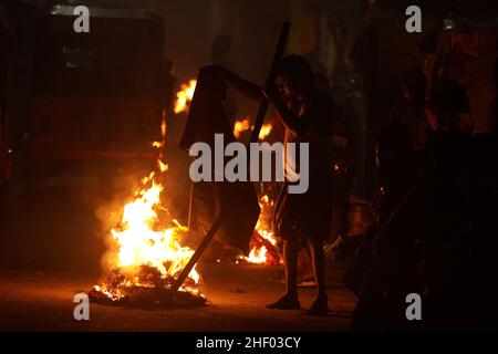 Chennai, Tamil Nadu, Indien. 13th Januar 2022. Ein Mann legt die alten Kleider in das Bhogi-Lagerfeuer, um das hinduistische Erntefest von Pongal in Chennai zu feiern. Bhogi ist der erste Tag des viertägigen Makara Sankranti Festivals. Auf Bhogi verwerfen die Menschen alte und veraltete Dinge und konzentrieren sich auf neue Dinge, die Veränderung oder Transformation verursachen. Menschen zünden Lagerfeuer mit Holzstämmen, alten Kleidern und Holzmöbeln zu Hause an, die nicht mehr nützlich sind. (Bild: © Sri Loganathan/ZUMA Press Wire) Stockfoto