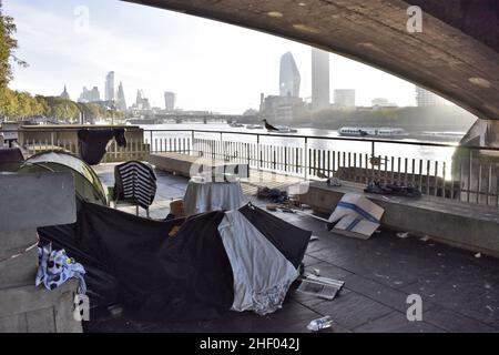 Obdachlose Zelte am Ufer der Themse unter der Waterloo-Brücke und moderne Wolkenkratzer im Hintergrund, London UK. Stockfoto