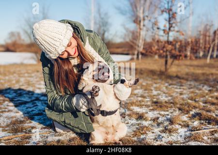 Junge Frau, die in einem verschneiten Winterpark einen Schwabenhund geht, spielt mit einem Haustier, das ein Tier auf den Hinterbeinen hält. Saisonale Aktivitäten im Freien Stockfoto