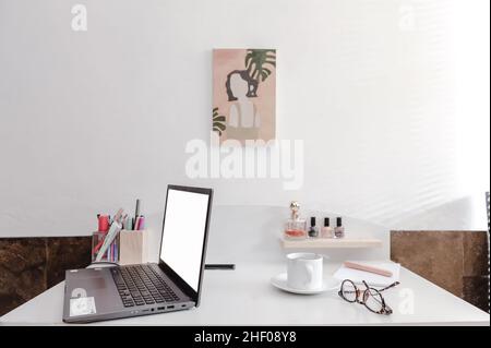 Laptop mit weißem Bildschirm auf einem ausgelasteten Tisch. Stockfoto