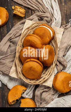 Hausgemachte Honigkekse gefüllte Creme. Süßes Dessert, unverzichtbare Zutat für die Teezeit. Alter Holzhintergrund, Draufsicht Stockfoto