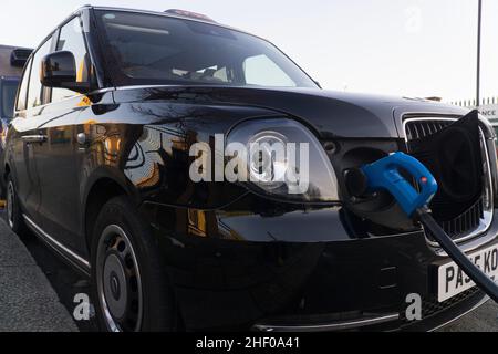 London, Großbritannien, 12. Januar 2022: Ein Elektrotaxi lädt an einer öffentlichen Ladestation. Obwohl dieses Fahrzeug wie ein traditionelles schwarzes Fahrerhaus aussieht, hat es geringe Emissionen und macht weniger Lärm. Anna Watson/Alamy Stockfoto