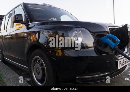 London, Großbritannien, 12. Januar 2022: Ein Elektrotaxi lädt an einer öffentlichen Ladestation. Obwohl dieses Fahrzeug wie ein traditionelles schwarzes Fahrerhaus aussieht, hat es geringe Emissionen und macht weniger Lärm. Anna Watson/Alamy Stockfoto