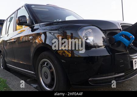 London, Großbritannien, 12. Januar 2022: Ein Elektrotaxi lädt an einer öffentlichen Ladestation. Obwohl dieses Fahrzeug wie ein traditionelles schwarzes Fahrerhaus aussieht, hat es geringe Emissionen und macht weniger Lärm. Anna Watson/Alamy Stockfoto