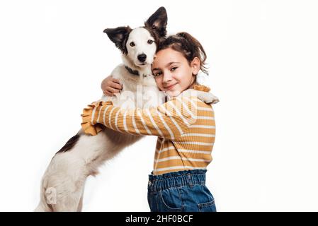 Ein junges Mädchen, das mit ihrem Mischlingshund die Kamera anschaut. Liebe zwischen Besitzer und Hund. Isoliert auf weißem Hintergrund. Stockfoto