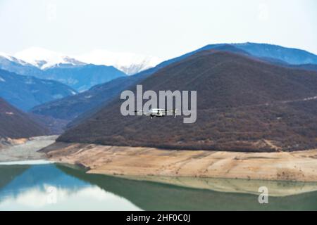 Der Stausee von Zhinvali in den Bergen Georgiens. Azurblaues Wasser auf einem Hintergrund von Bergen. Die Drohne fliegt und macht Bilder von der schönen Aussicht auf Stockfoto