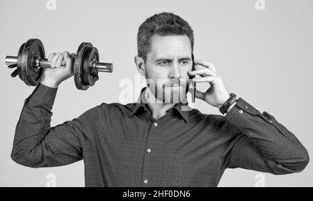 Kommunikation. Gutaussehender Geschäftsmann mit Hantel sprechen am Telefon. Digitaler Sport. Stockfoto