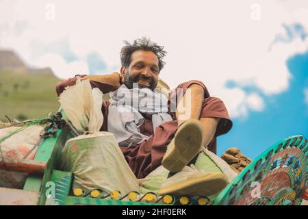 Gilgit, Pakistan - 08. Juni 2020: Lehnt sich an den hellen traditionellen Truck Smiling man Stockfoto