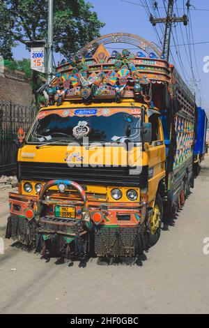 Lahore, Pakistan - 1. Juli 2020: Heller und farbenfroher gelber pakistanischer LKW mit traditioneller Dekoration und Design auf der Lahore Street Stockfoto