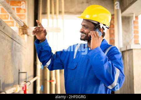 Lächelnder Klempner beim Telefonieren am Arbeitsplatz – Konzept der Pause bei der Arbeit, Kommunikation und Service. Stockfoto