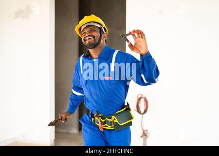 Reparaturman tanzt mit Werkzeug in der Hand für den erfolgreichen Abschluss der Arbeit - Konzept Glück, fröhlichen Lebensstil, genießen Sie die Arbeit und Pause während Stockfoto