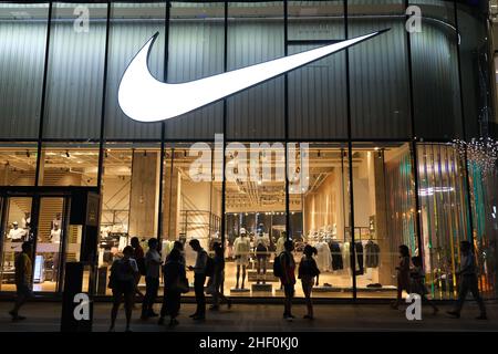 ‘Nike Store bei Nacht mit der Silhouette vieler Menschen. Amerikanische Sportmarke Stockfoto