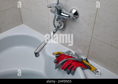 Verstellbare Klempnerschlüssel und Klempnerhandschuhe in der Dusche Stockfoto