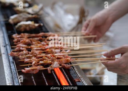 Nahaufnahme von Hand Kochen Grill auf dem Grill. Soft Focus Stockfoto